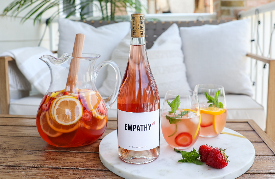 A bottle of Empathy rose on a marble board with a jug of sangria 