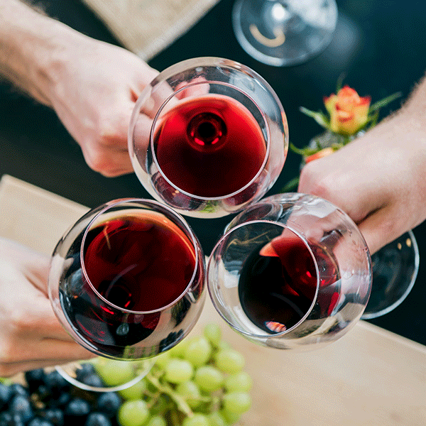 Three people clink their glasses of red wine. Cheers!